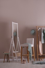 Photo of Modern dressing room interior with clothing rack, stool and mirror