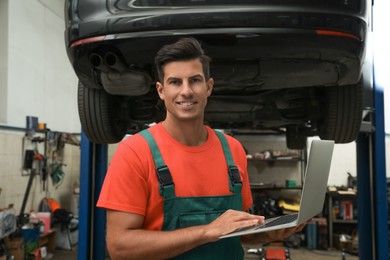 Photo of Mechanic with laptop for car diagnostic at automobile repair shop