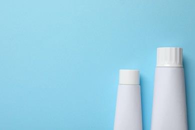 Photo of Blank tubes of toothpaste on light blue background, flat lay. Space for text