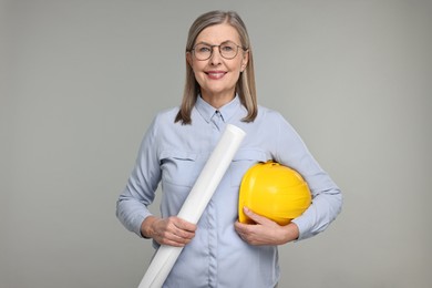 Photo of Architect with hard hat and draft on grey background