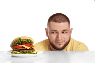 Photo of Young man and tasty burger on white background