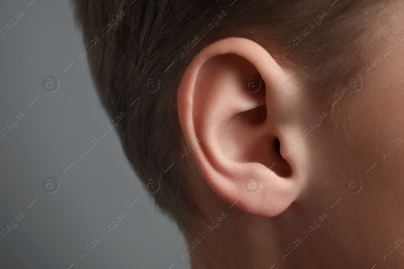 Photo of Boy on grey background, closeup of ear