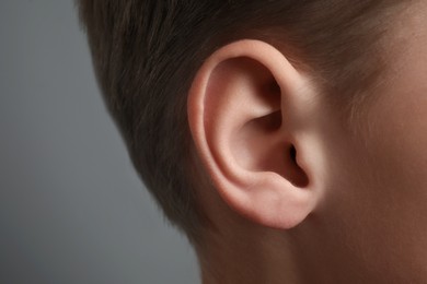 Boy on grey background, closeup of ear