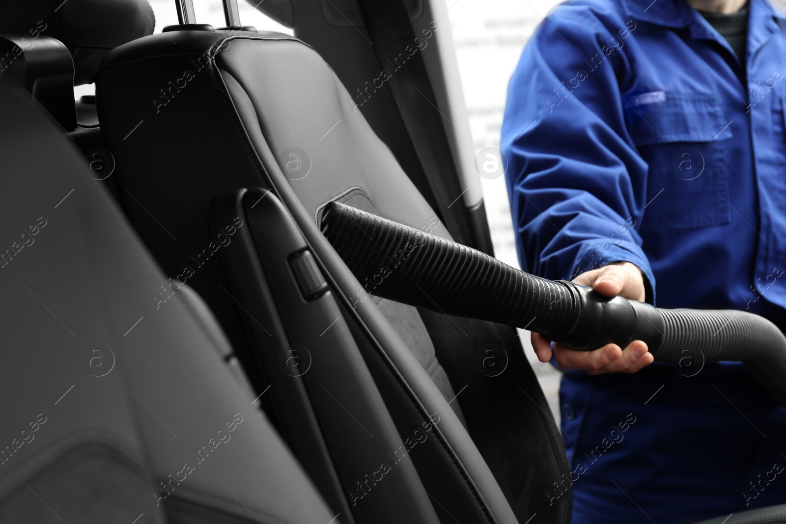 Photo of Car wash worker vacuuming automobile seat, closeup