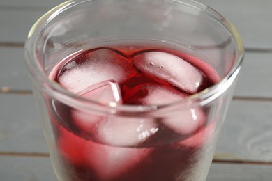 Photo of Refreshing hibiscus tea with ice cubes in glass on table, closeup