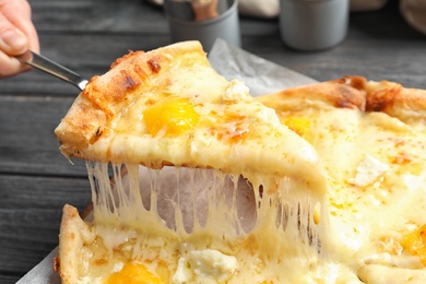 Photo of Woman taking slice of hot cheese pizza Margherita on table, closeup