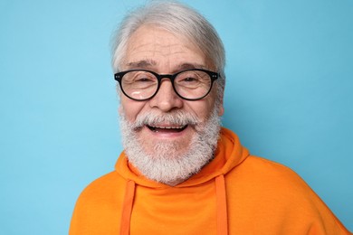 Senior man with mustache on light blue background