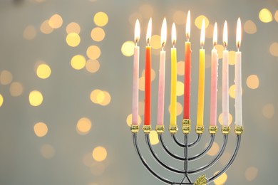 Photo of Hanukkah celebration. Menorah with burning candles against blurred lights, space for text