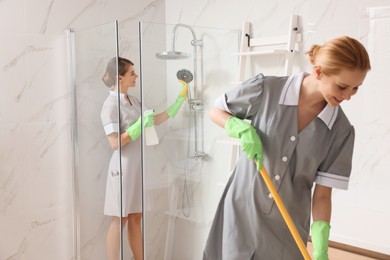 Photo of Professional chambermaids cleaning up bathroom in hotel