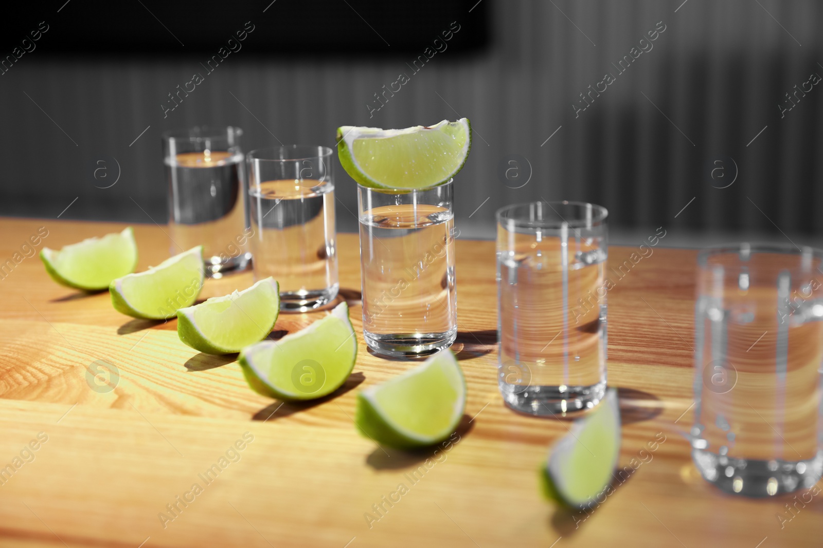 Photo of Vodka shots and lime slices on wooden bar counter