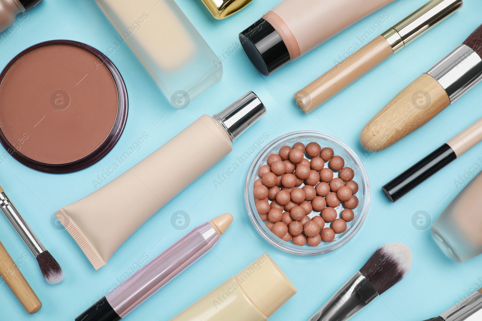 Photo of Face powders and other decorative cosmetic products on light blue background, flat lay