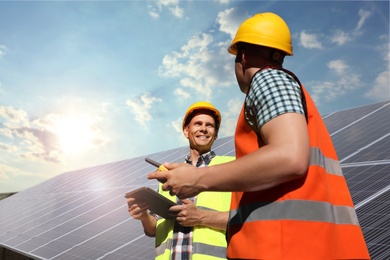 Image of Engineers near solar panels outdoors. Alternative energy source