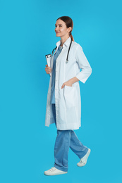 Photo of Doctor with clipboard and stethoscope walking on blue background