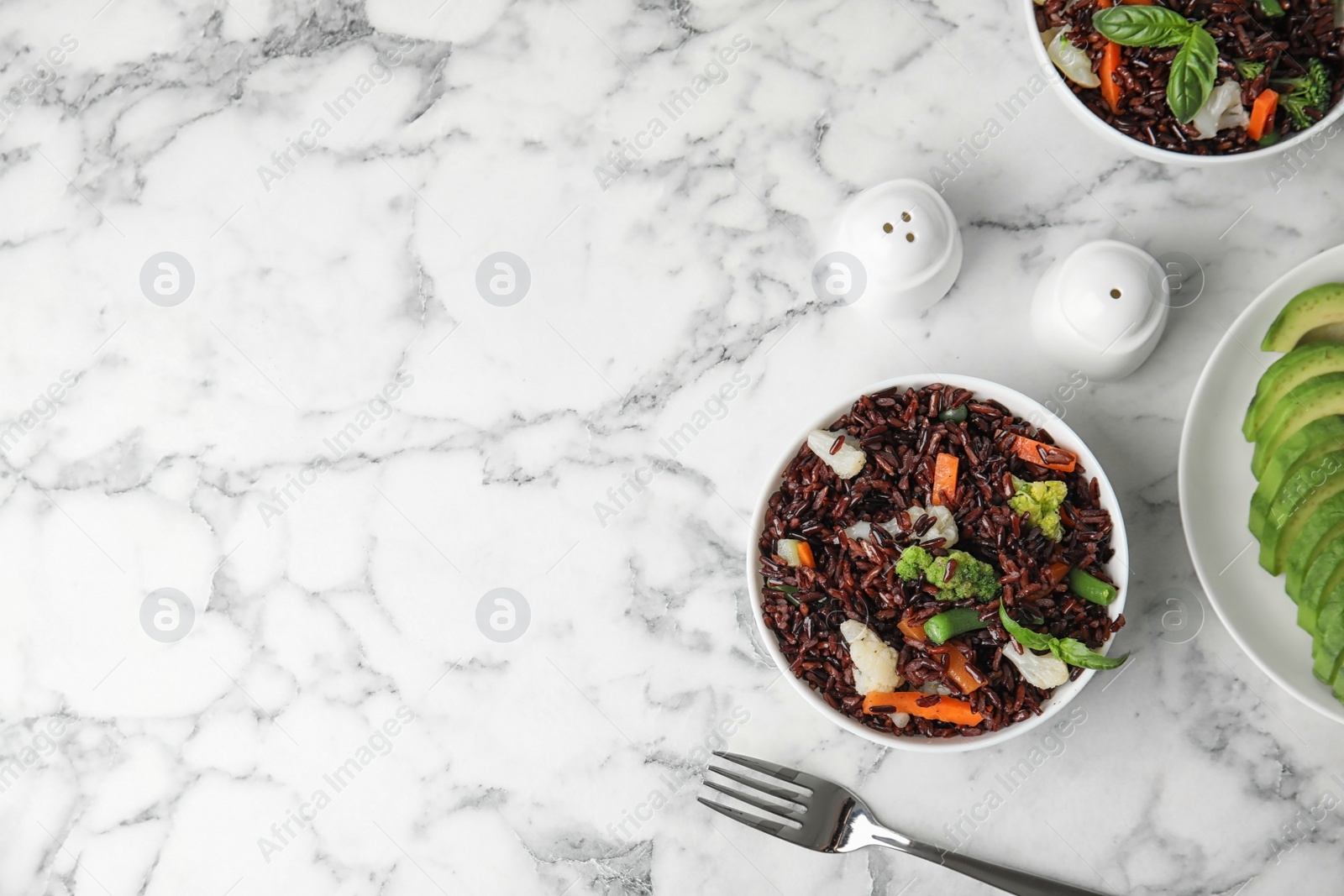 Photo of Bowl of brown rice with vegetables on marble table, flat lay. Space for text