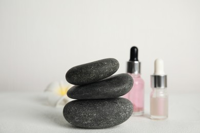 Photo of Stack of grey spa stones, oils and flower on white table