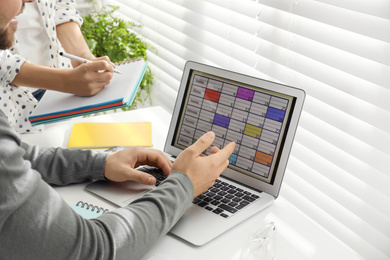 Colleagues working with calendar app on laptop in office, closeup