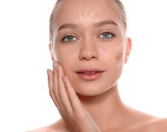 Young woman with different shades of skin foundation on her face against white background