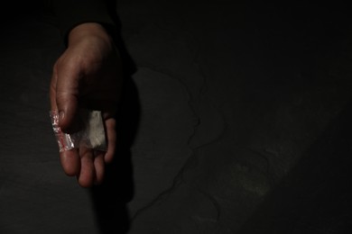 Photo of Addicted man with plastic bag of hard drug at grey textured table, top view. Space for text