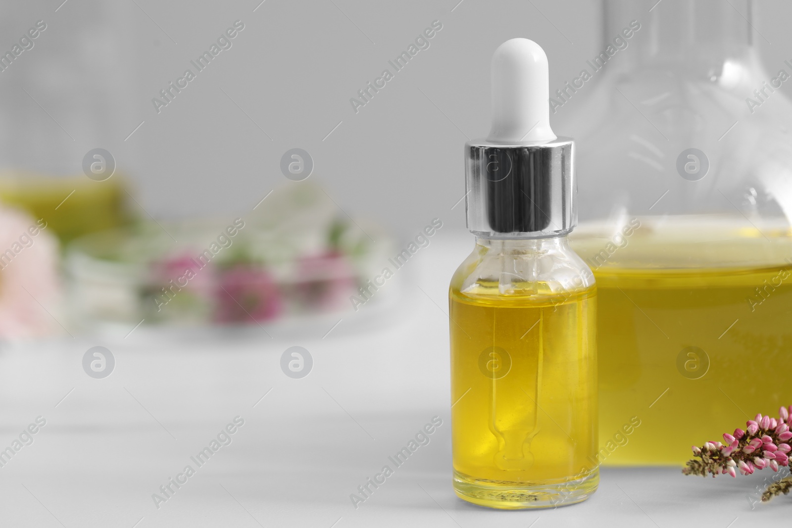 Photo of Bottle of cosmetic oil on white table, closeup. Space for text