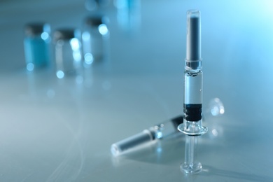 Syringes with COVID-19 vaccine on light table, space for text