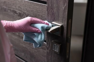 Photo of Woman wiping door handle with rag, closeup