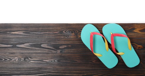 Turquoise flip flops and space for text on wooden table against white background, top view