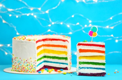 Photo of Delicious rainbow cake on table against blurred lights