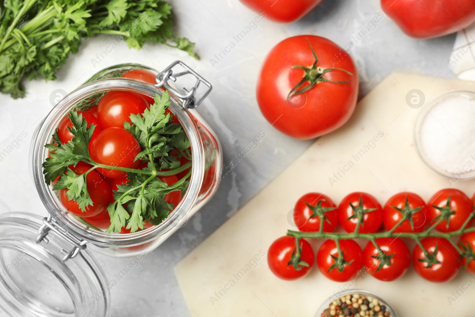 Photo of Pickling jar with fresh ripe cherry tomatoes and spices on grey table, flat lay