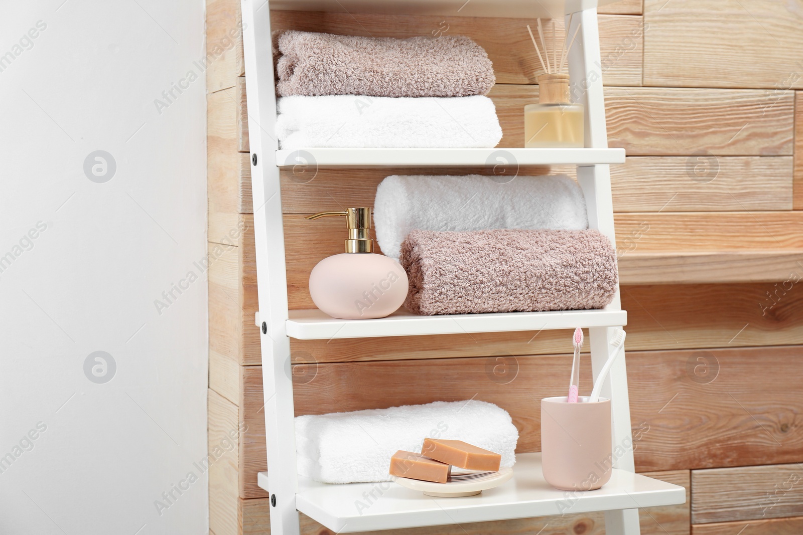 Photo of Towels, toiletries and soap dispenser on shelves in bathroom