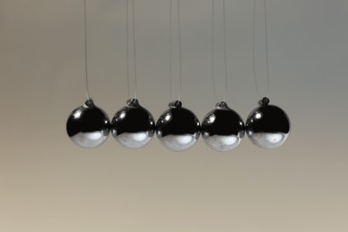 Photo of Newton's cradle on grey background. Physics law of energy conservation