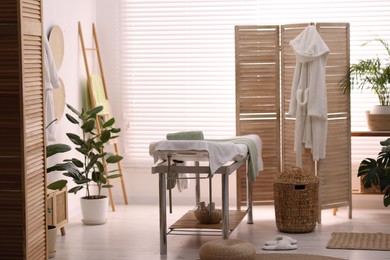 Comfortable massage table with clean towels in spa center