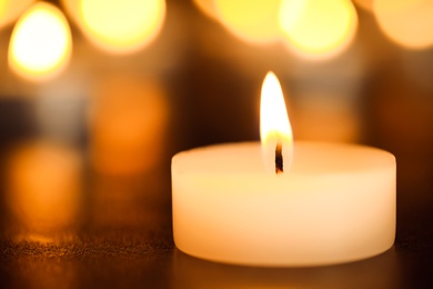 Burning candle on table, closeup. Funeral symbol
