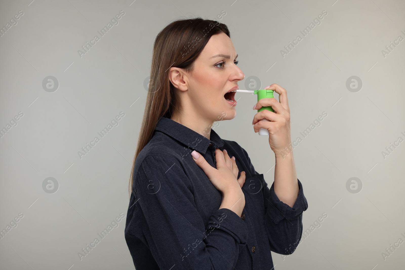 Photo of Woman using throat spray on grey background