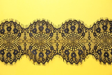 Black lace on yellow background, top view