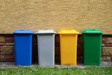 Photo of Many colorful recycling bins near yellow wall outdoors