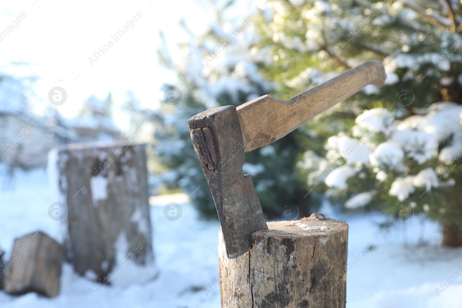 Photo of Metal axe in wooden log outdoors on sunny winter day. Space for text