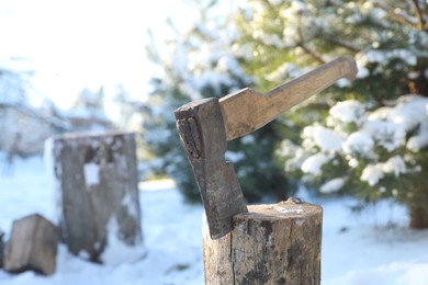 Metal axe in wooden log outdoors on sunny winter day. Space for text