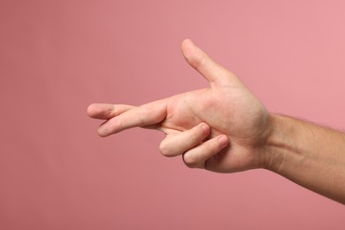 Photo of Man crossing his fingers on pink background, closeup