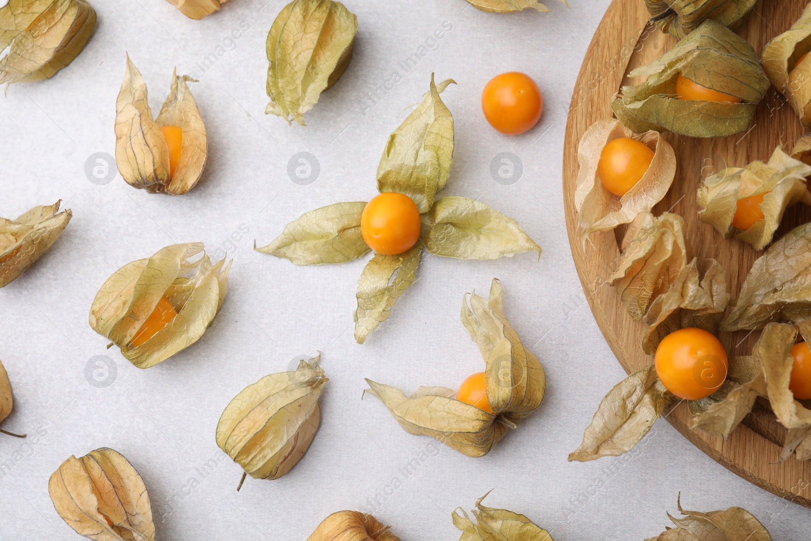 Photo of Ripe physalis fruits with calyxes on white table, flat lay. Space for text