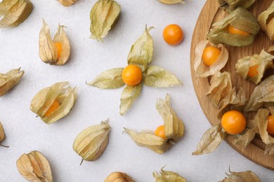 Ripe physalis fruits with calyxes on white table, flat lay. Space for text