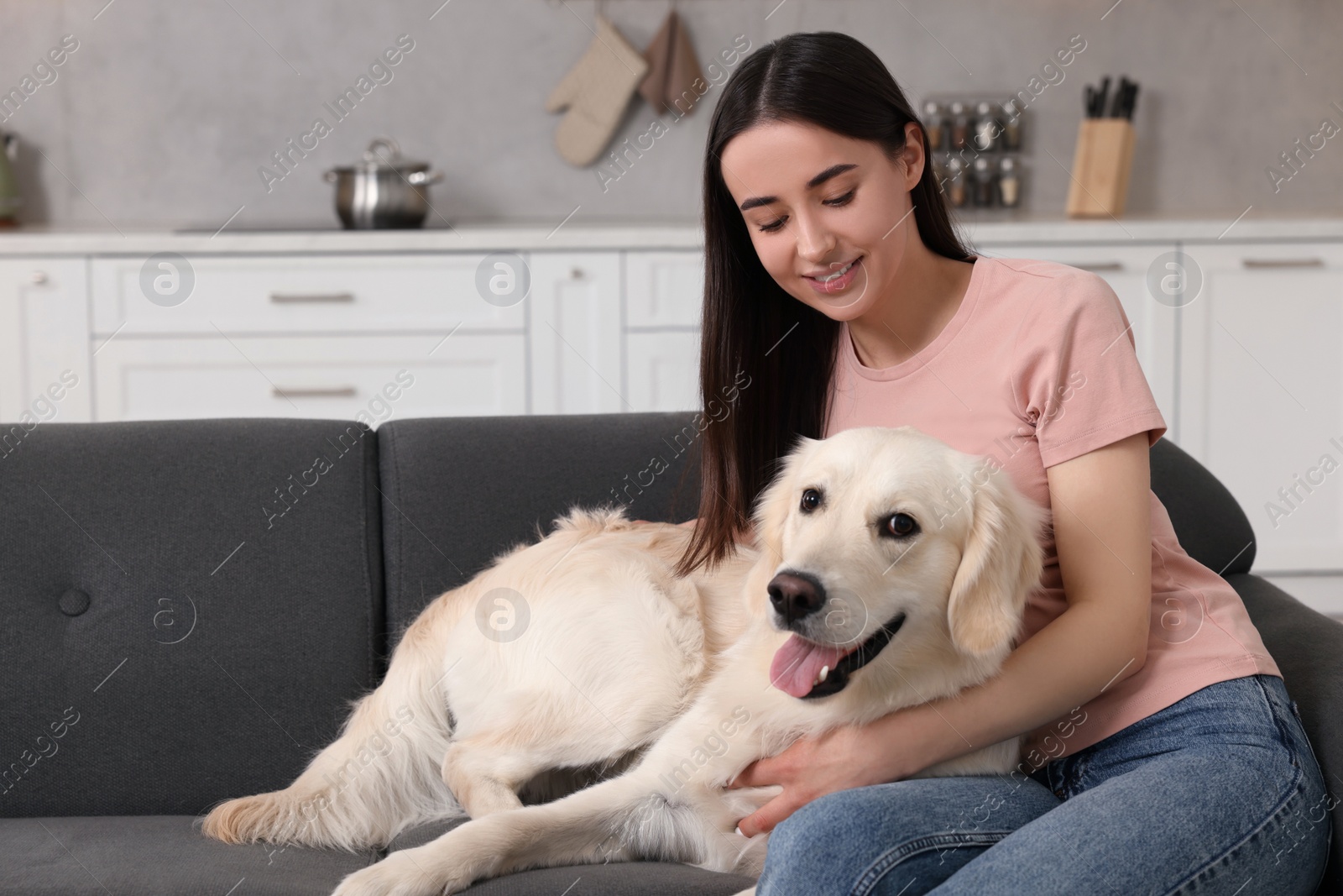 Photo of Happy woman with cute Labrador Retriever dog on sofa at home. Adorable pet