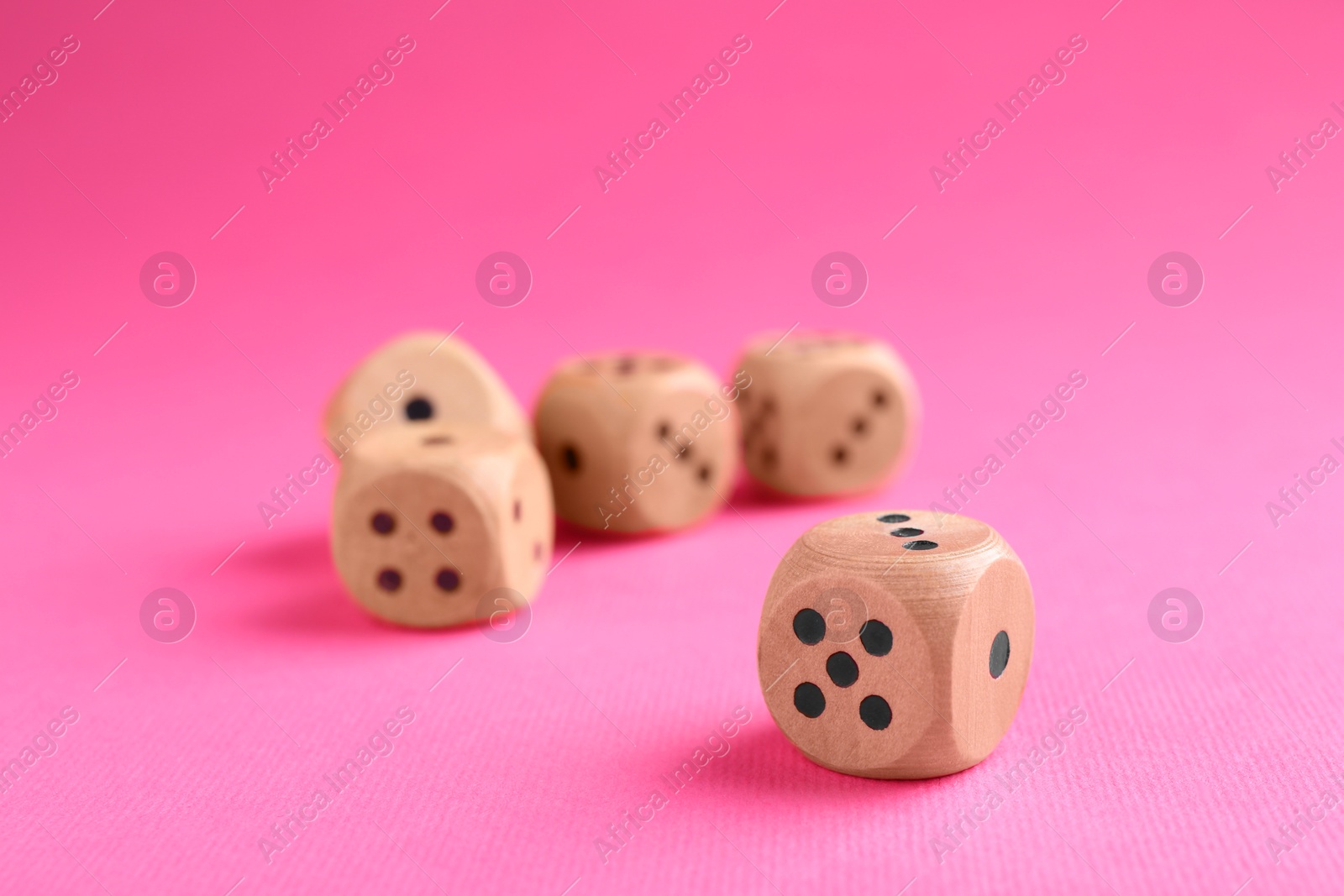 Photo of Many wooden game dices on pink background, closeup