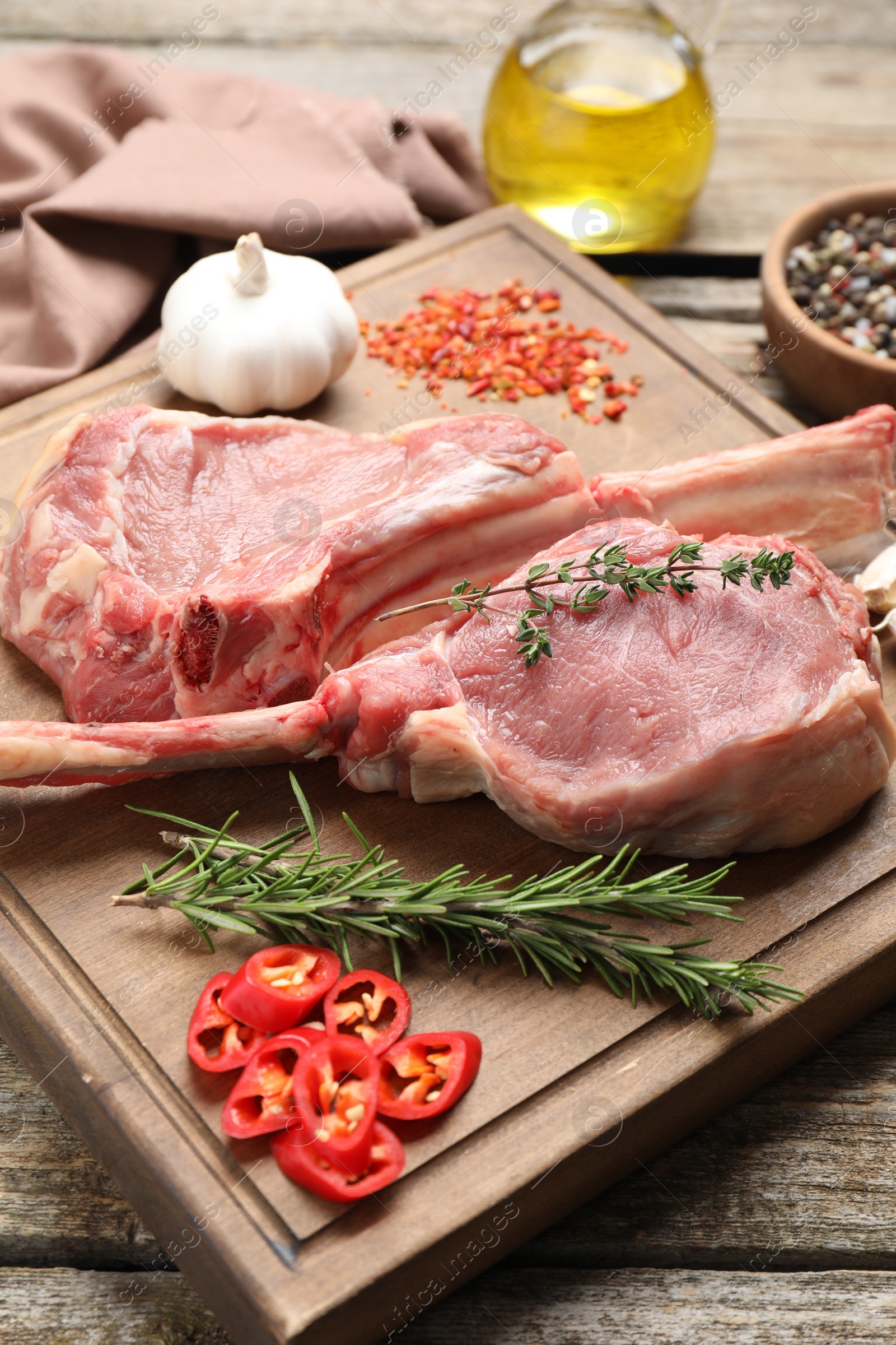 Photo of Fresh tomahawk beef cuts and spices on wooden table