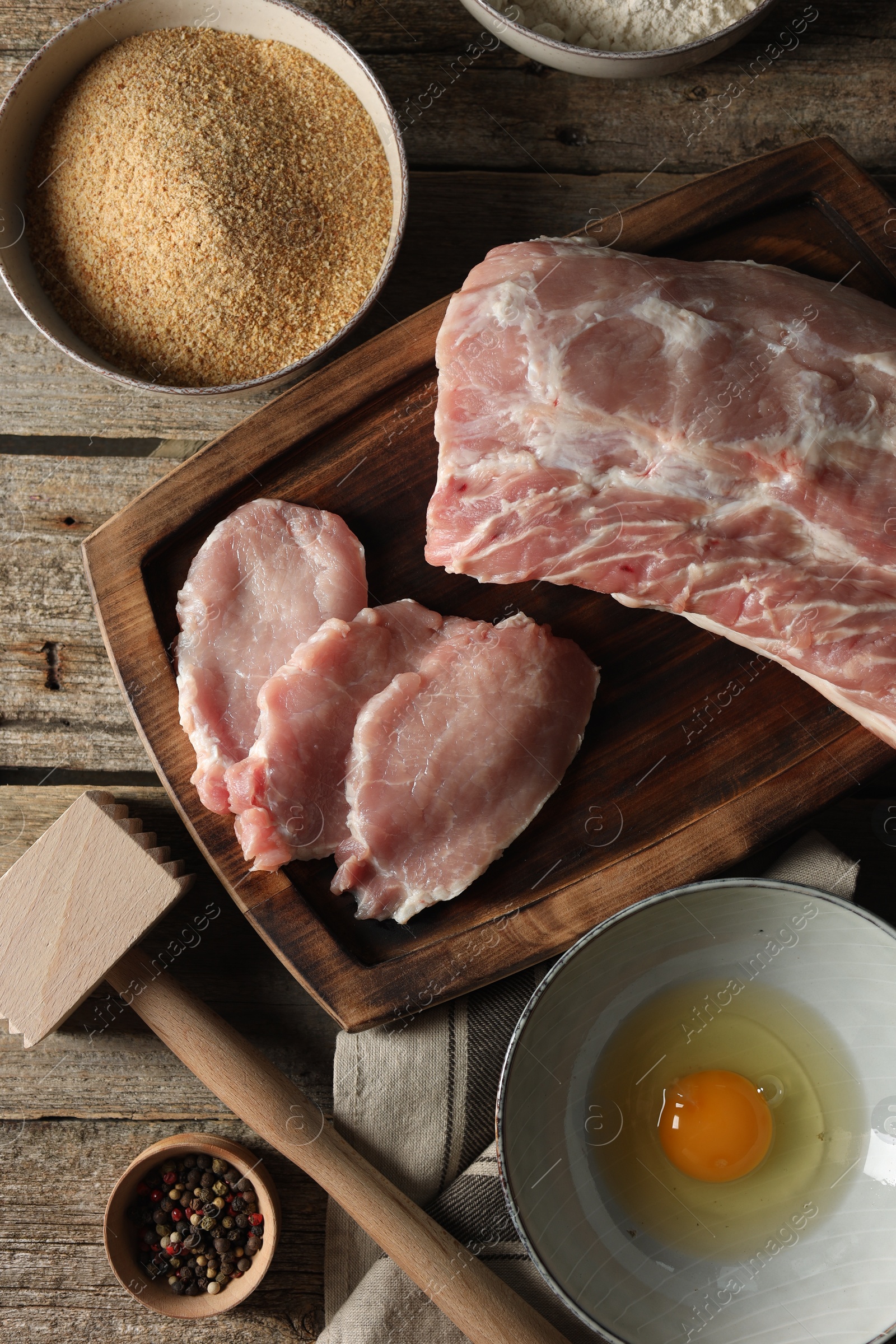 Photo of Different ingredients for cooking schnitzel on wooden table, flat lay