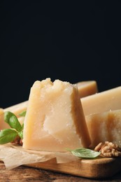 Photo of Delicious parmesan cheese with walnuts and basil on wooden table, closeup