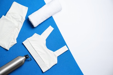 Photo of Stylish sportswear, bottle of water and yoga mat on white background, flat lay