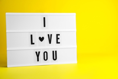 Photo of Decorative lightbox with phrase I love You on yellow background. Space for text