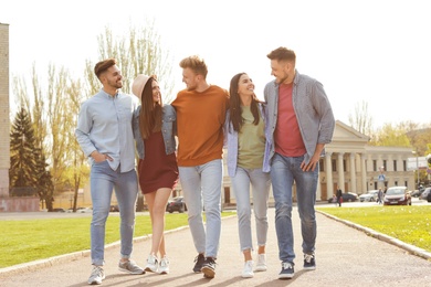 Happy people walking outdoors on sunny day