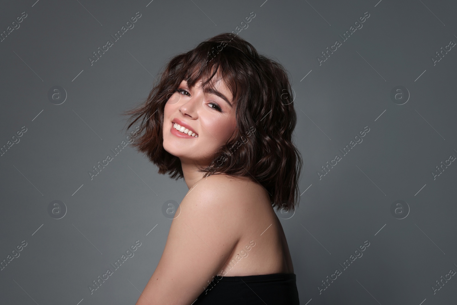 Photo of Portrait of beautiful young woman with wavy hairstyle on grey background