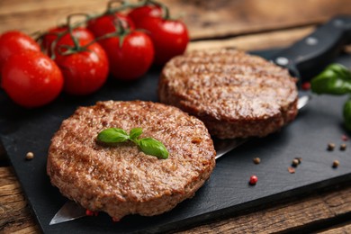 Tasty grilled hamburger patties served on wooden table, closeup